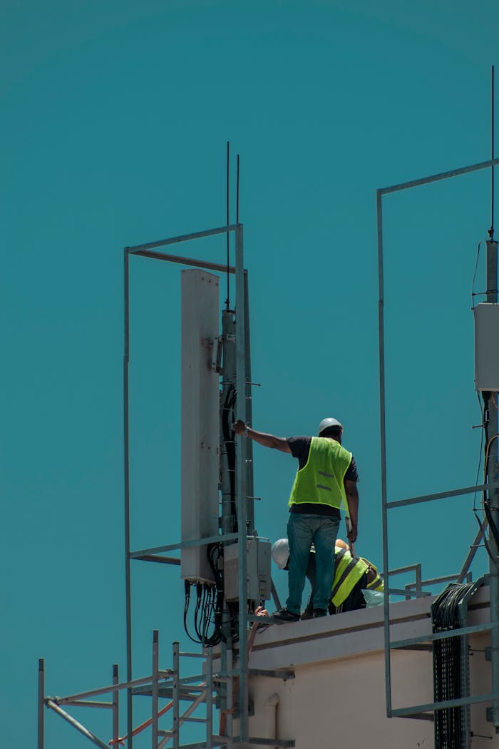 services-03 Workers in safety vests on a rooftop in Dubai, installing equipment. Vertical shot.